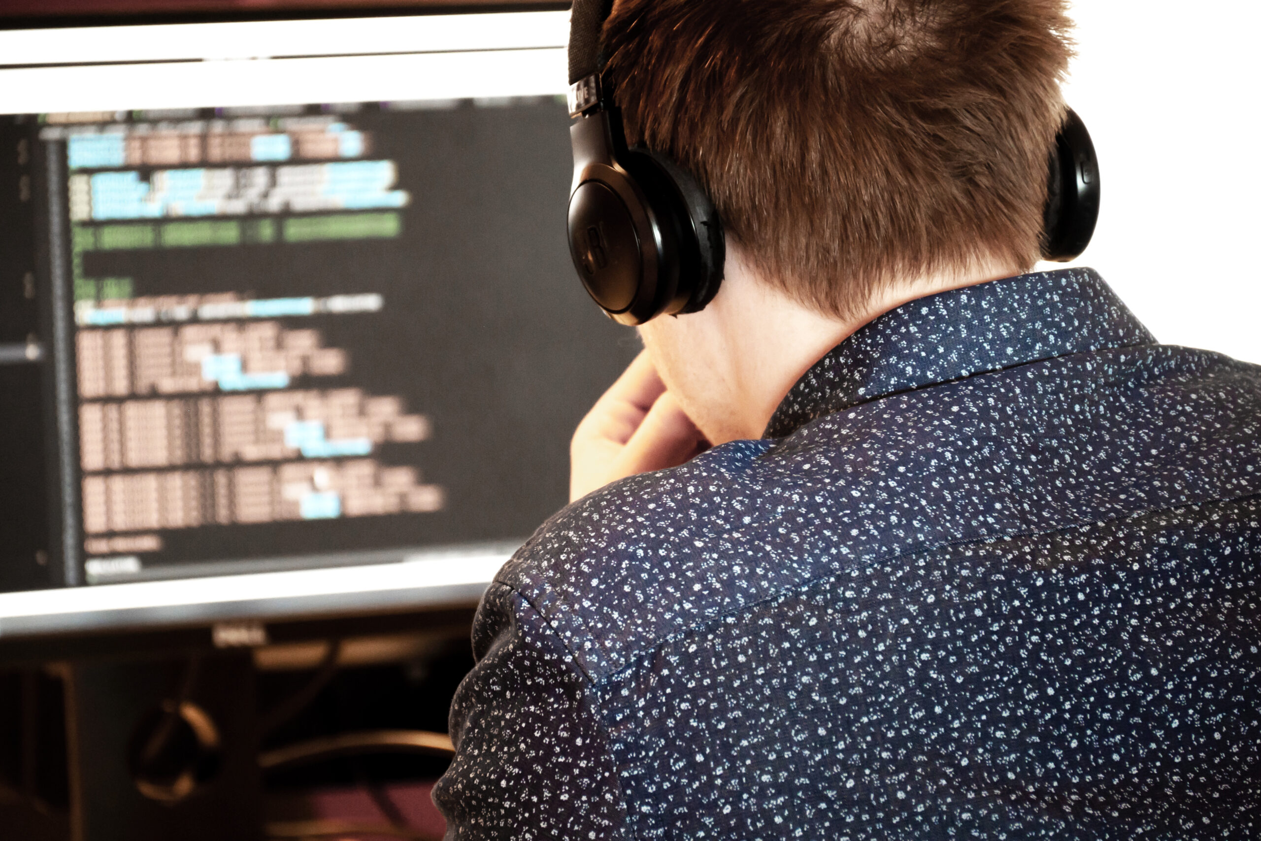 Man lookin at a laptop wearing headphones